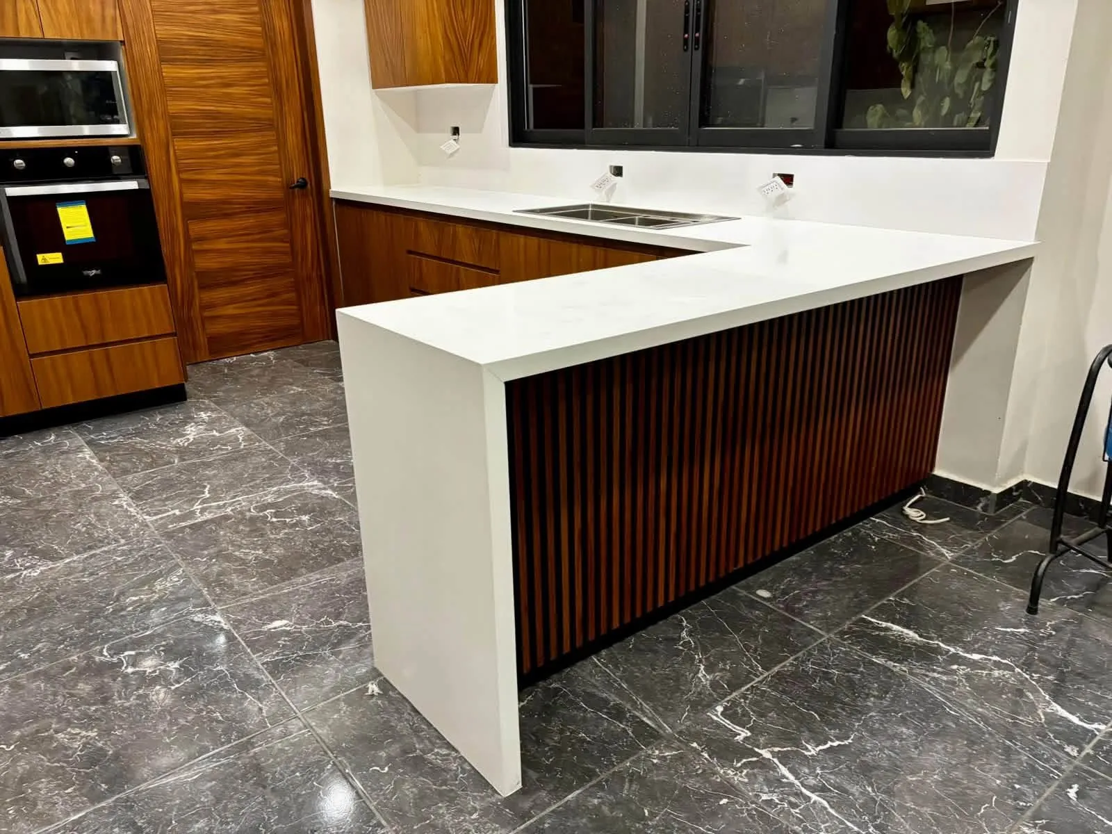 Cocina con península blanca y panel acanalado de madera