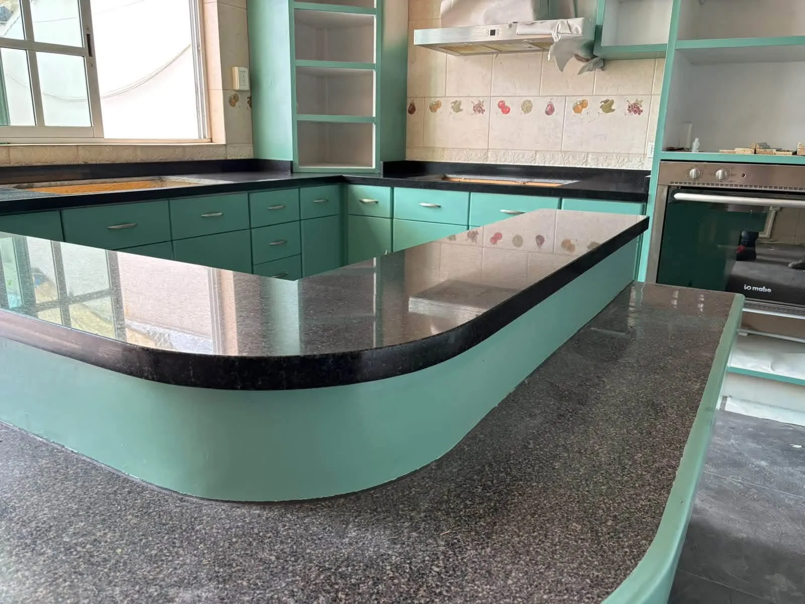 Barra curva negra en cocina con carpintería verde